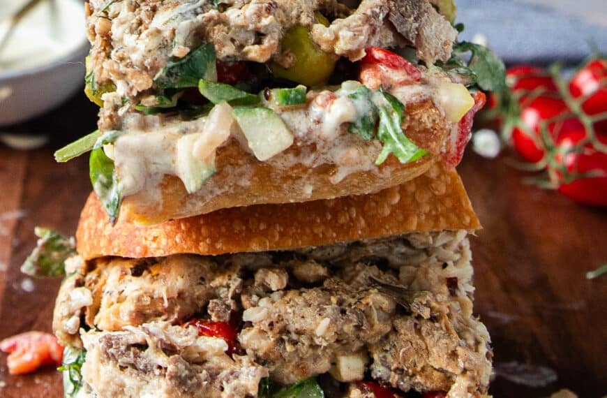 Cut up sardine sandwich in half close up shwoing the layers of sardines and fresh ingredients stuffed inside the sandwich bread
