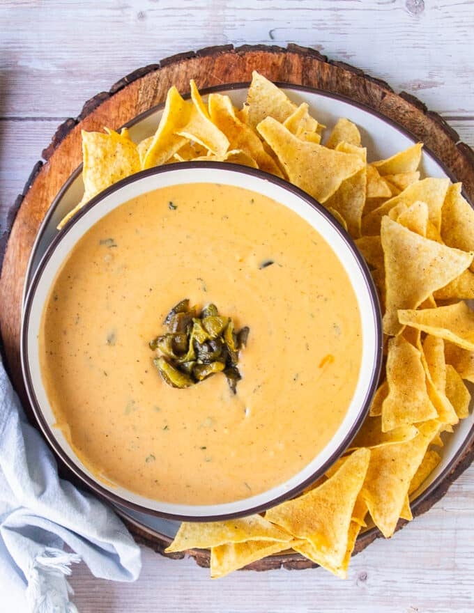 Top view of a bowl of smoky queso recipe alongside some chips for serving