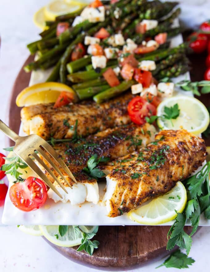 A fork flaking succulent air fryer cod showing how perfectly cooked in the air fryer