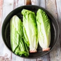 Romaine lettuce halves on the grill cut side down.