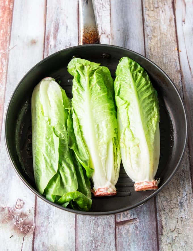 Romaine lettuce halves on the grill cut side down.