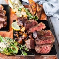 A full plate of pincanha steaks served with potato wedges and grilled romaine salad with the meat sliced perfectly to show how perfect done