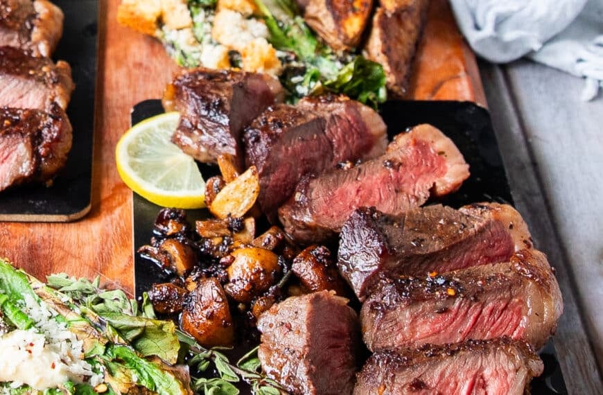 A full plate of pincanha steaks served with potato wedges and grilled romaine salad with the meat sliced perfectly to show how perfect done