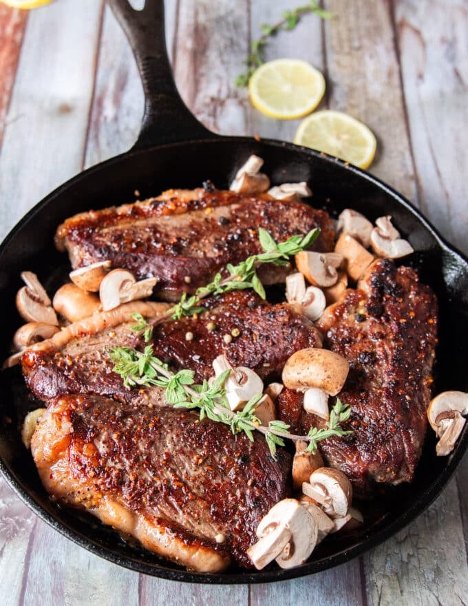 Mushrooms and whole garlic cloves, butter and herbs are aded to the picanha steaks