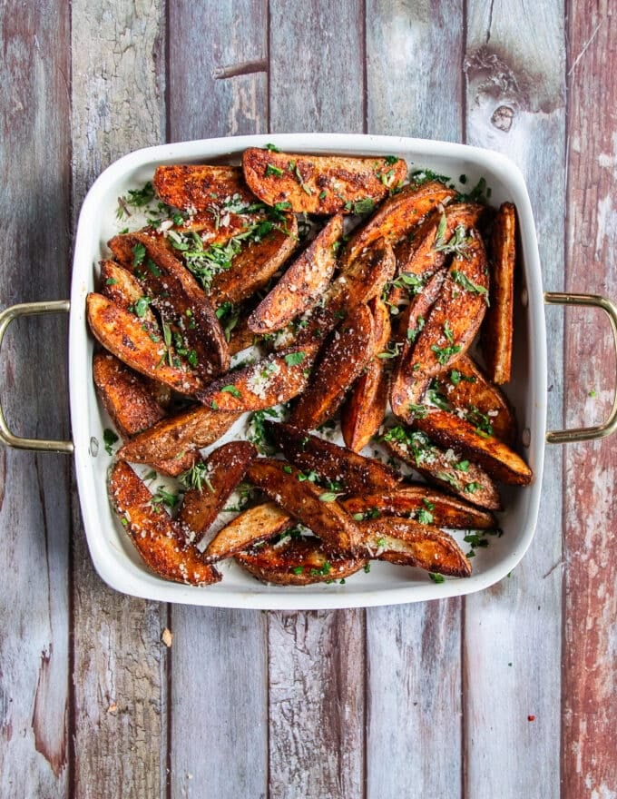 top view of a finished plate of potato wedges finished with parmesan cheese and some parsley