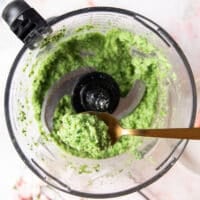 ready broccoli pesto in a food processor and a spoon tasting it