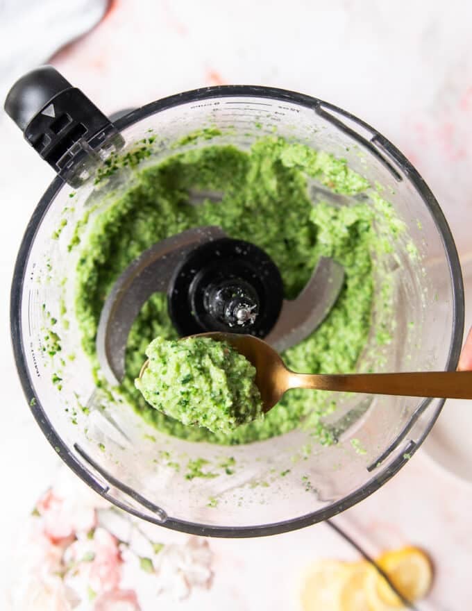 ready broccoli pesto in a food processor and a spoon tasting it