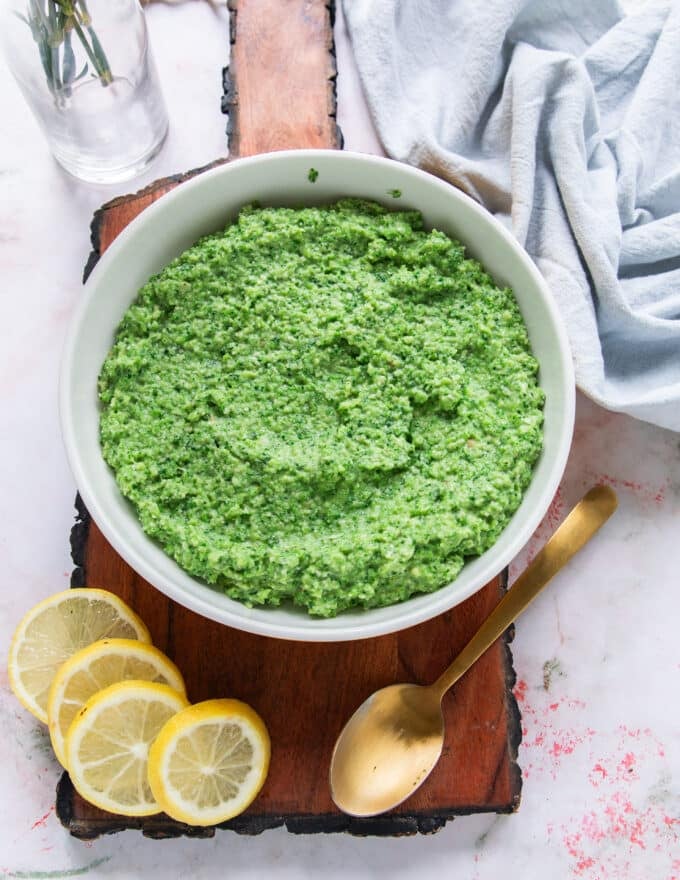 A close up of a bowl of broccoli pesto showing the texture and vibrant green color