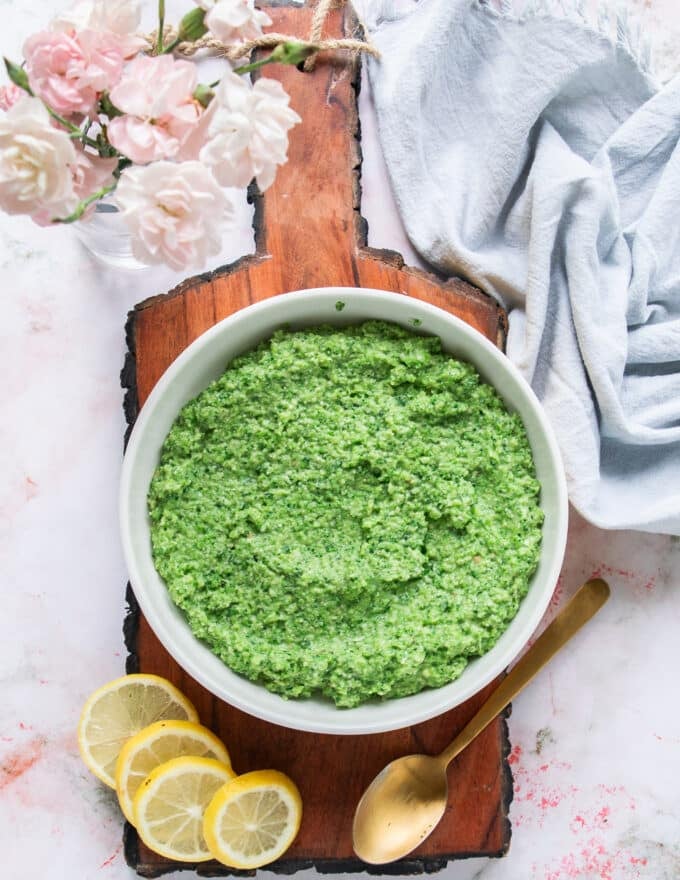 A bowl of broccoli pesto surrounded by lemon slices