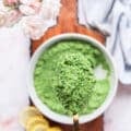 A spoon holding a close up of broccoli pesto