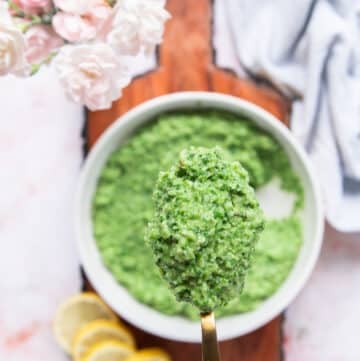 A spoon holding a close up of broccoli pesto