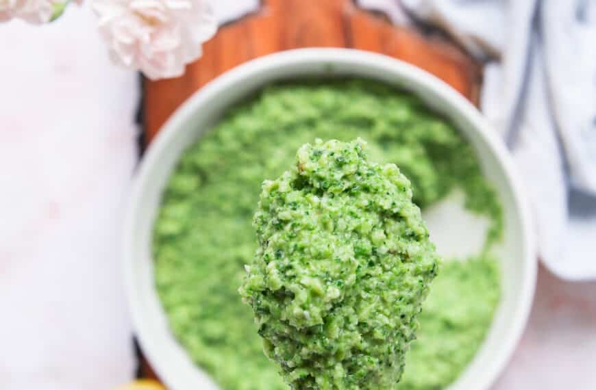 A spoon holding a close up of broccoli pesto