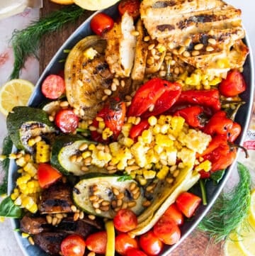 A platter of grilled chicken salad with grilled veggies and a simple lemon dressing