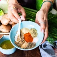 The dry seasoning blend in a large bowl, a hand whisking them together