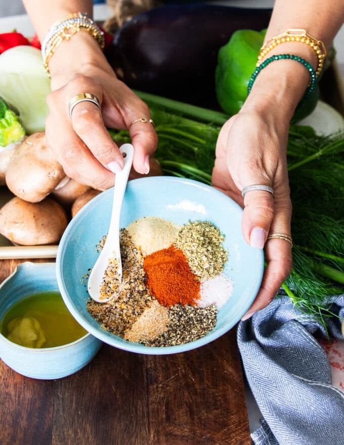 The dry seasoning blend in a large bowl, a hand whisking them together