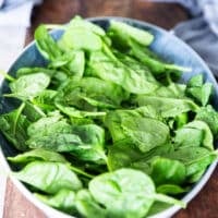 Spinach and greens spread at the bottom of the dish to layer the chicken salad