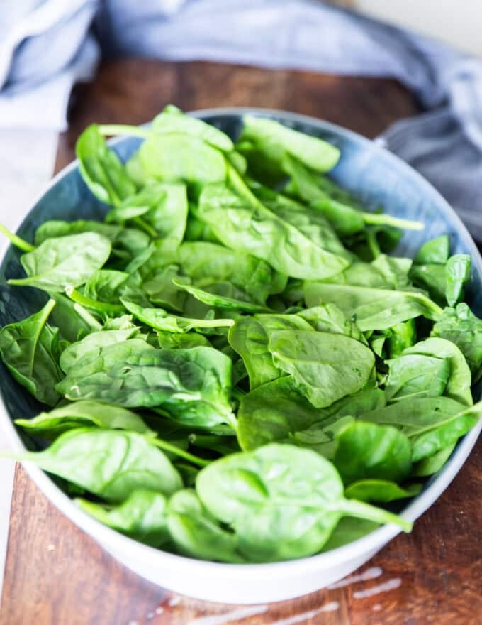 Spinach and greens spread at the bottom of the dish to layer the chicken salad