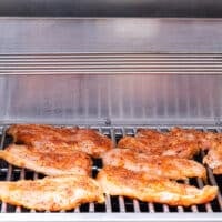 The chicken and veggies placed on an outdoor grill