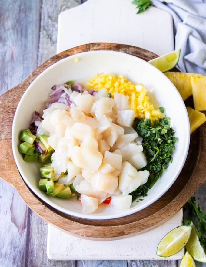 The diced scallops are added over the bowl of ceviche ingredients and ready to mix