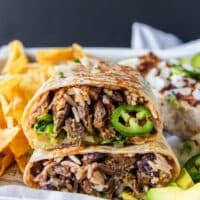 sliced burrito in half showing the filling close up and the consommé dip