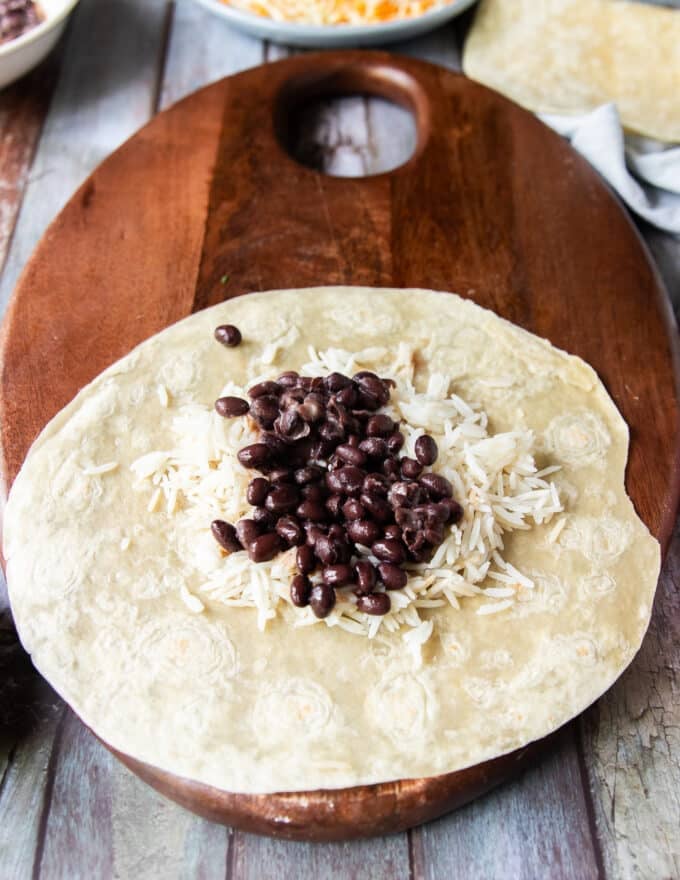 birria burrito fillings loaded, starting with rice and black beans