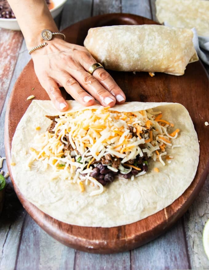 rolling the perfect burrito step by step beginning by folding one edge over half the filling 
