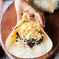 continuing to roll the burrito : both sides of the tortillas are now gathered to make sure the filling doesn't ooze out
