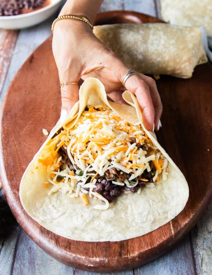 continuing to roll the burrito : both sides of the tortillas are now gathered to make sure the filling doesn't ooze out 
