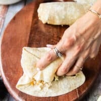 Continuing to roll the burrito, both sides and front are clumped together to enclose the filing fully