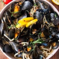 close up of a mussel pasta bowl with lemon slices and perfectly cooked mussels