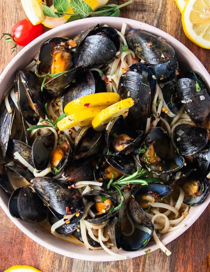 close up of a mussel pasta bowl with lemon slices and perfectly cooked mussels