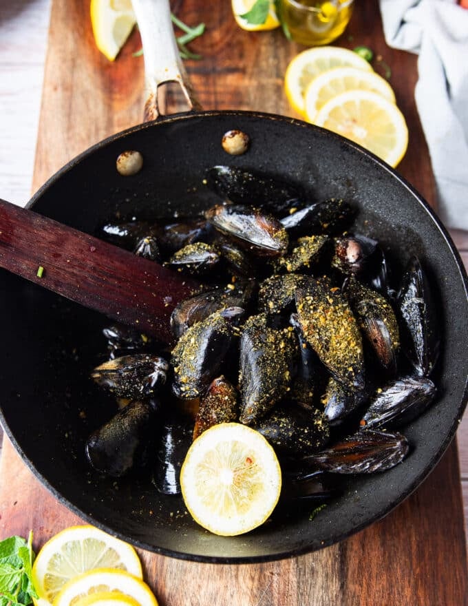 The mussels, seasoning and lemon slice is added to the skillet to make the sauce