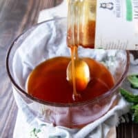 A jar of honey being poured into a glass jar to begin whipping