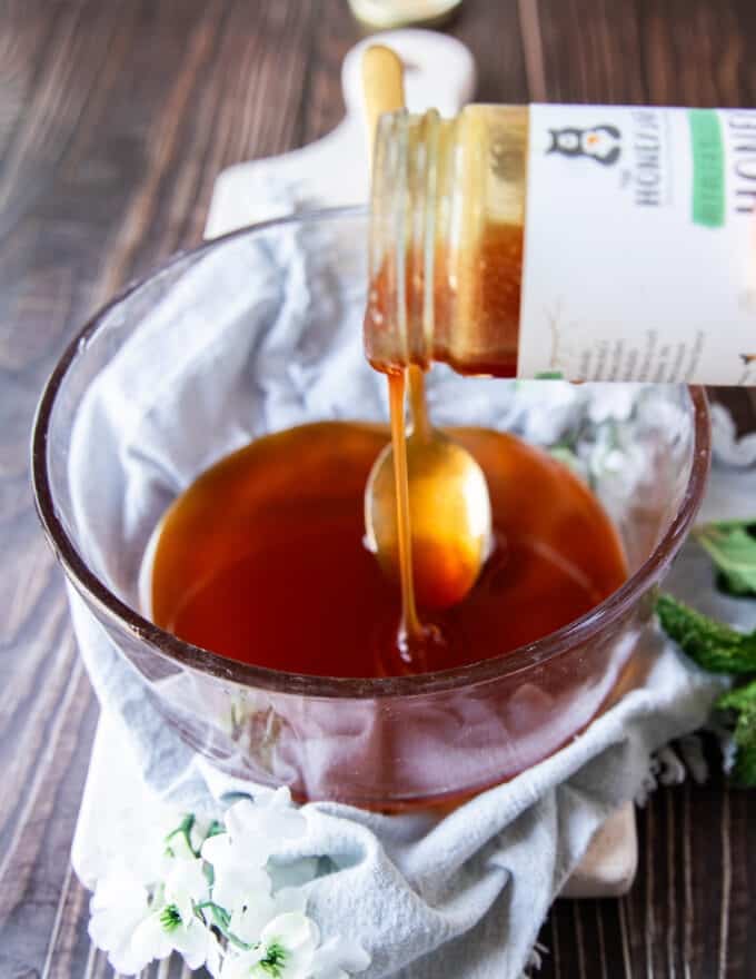 A jar of honey being poured into a glass jar to begin whipping
