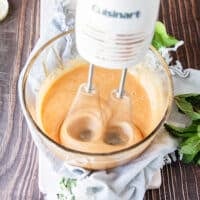 a hand held mixer whipping the honey in a glass bowl