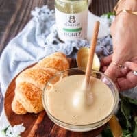 A bowl of whipped honey next to a croissant for spreading
