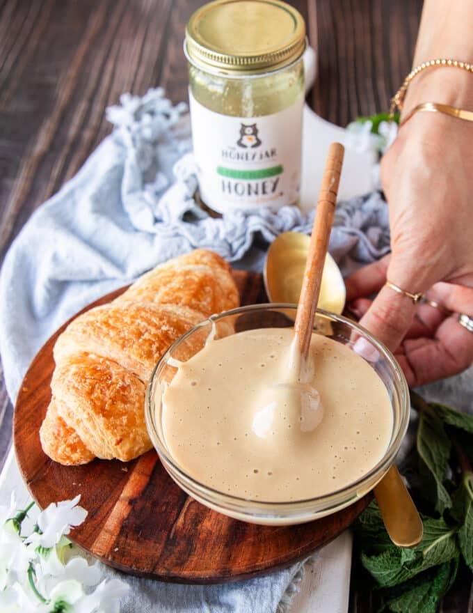 A bowl of whipped honey next to a croissant for spreading